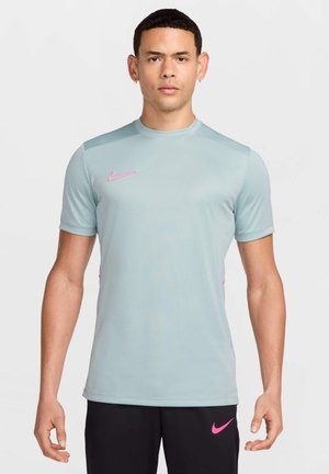 Helles blaues kurzärmliges Sportshirt mit Rundhalsausschnitt und pinkem Nike-Logo auf der Brust. Glatte Textur und figurbetontes Design.