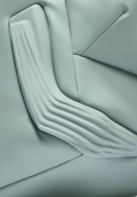 Material de color verde claro similar al cuero, con un acento texturizado y ondulado y detalles de costura, que presenta un diseño moderno y suave.