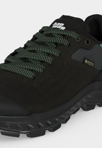 Μαύρο πεζοπορικό παπούτσι Gore-Tex με υφασμένο πέλμα, κορδόνια με πράσινο και μαύρο σχέδιο, και λογότυπο «hanwag» στη γλώσσα.