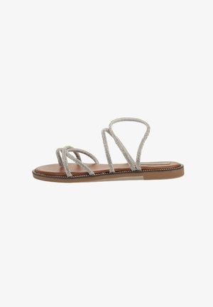 Sandalia plana con tiras plateadas metálicas entrelazadas, plantilla de imitación de cuero marrón y suela de goma marrón claro. Diseño minimalista y punta abierta.