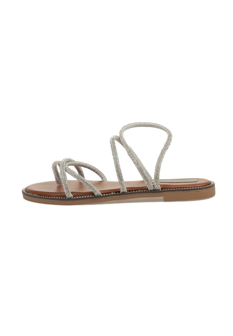 Sandalia plana con tiras plateadas metálicas entrelazadas, plantilla de imitación de cuero marrón y suela de goma marrón claro. Diseño minimalista y punta abierta.