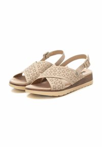 Sandalias beige con un diseño perforado, correa ajustable para el tobillo, un leve tacón y suela texturizada para mayor agarre. Presentan recortes florales.