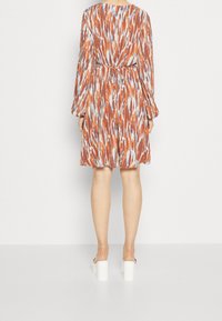 Vestido de manga corta y largo hasta la rodilla con un patrón abstracto multicolor en naranja, azul y blanco, que presenta un detalle de cintura atada y un ligero vuelo.
