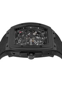 Czarny szkieletowy zegarek z prostokątną kopertą, przezroczystą tarczą ukazującą mechanikę wewnętrzną, teksturowanym paskiem oraz pokrętłem do nakręcania po boku.