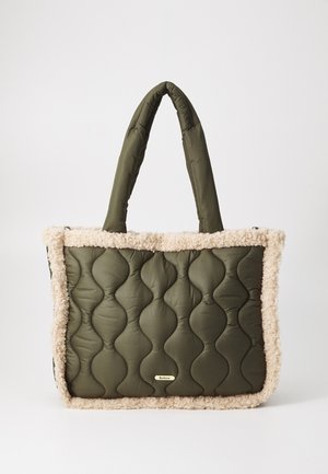 Sac fourre-tout matelassé vert olive avec des bords en beige peluche et des poignées en tissu doubles. Présente une plaque logo dorée à l'avant. Fermeture éclair.