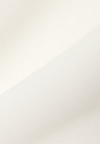 Lähikuva tasaisesta, valkoisesta, teksturoidusta kankaasta, jossa on hienovaraisia vinottain taitoksia ja pehmeä valaistus korostamassa sen kudottua pintaa.