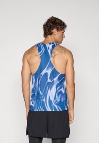 Blau-weißer, gemusterter Tanktop mit atmungsaktivem Design, ausgestattet mit einem Racerback-Schnitt und glattem Stoff. Dazu werden schwarze Shorts getragen.
