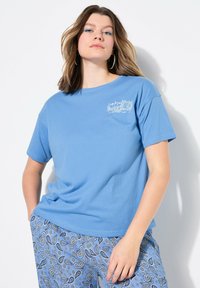 Lichtblauw katoenen T-shirt met een ronde hals, korte mouwen en een borstzakafbeelding. Gecombineerd met blauw gestreepte broek met een paisley ontwerp.