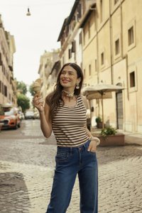 Stribet tanktop, blå denimjeans, isvaffel med lysebrun is, vedhængsoresmykker, blomsterchoker, brostensbelagt gade.