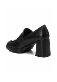 Mocassini neri in pelle con tacco largo, punta rotonda e dettagli decorativi della fascia. Texture liscia con accenti minimi.