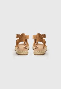 Tan semskinn espadrillesandaler med en vevd jutesåle, åpen bak, og justerbare ankelremmer med detaljer i gulltone.