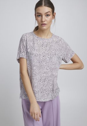 T-shirt à manches courtes en violet clair avec un motif tacheté noir et blanc ; col rond et coupe décontractée.
