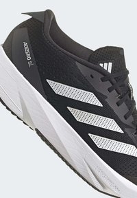 Chaussure de running Adidas Adizero SL noire avec semelle blanche et trois bandes blanches perforées sur le côté, lacets noirs et languette marquée.
