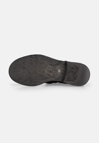 Suela de zapato negra con superficie texturizada, mostrando un borde cosido. Material de goma con patrón de grano sutil y tamaño marcado como 37.