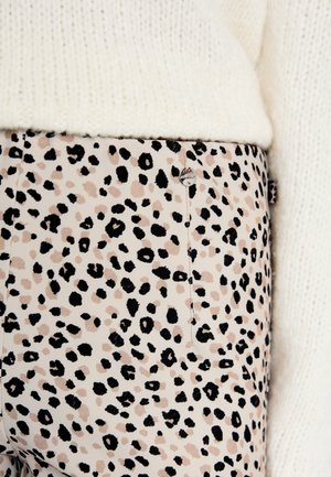 Schmale Hosen aus einem beigen Stoff mit einem schwarzen und braunen Leopardenmuster. Sie verfügen über einen sichtbaren Metallknopf und eine Nahtdetails.