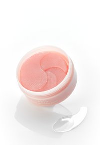 Pot rond de patches pour les yeux roses, avec une surface texturée. Comprend une spatule d'application transparente à côté du pot.