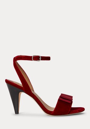 Sandale à talon haut en velours rouge avec bride à la cheville et boucle, bout ouvert, et talon noir empilé en forme de cône.