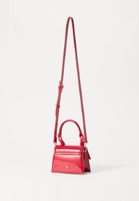 Sac à main en cuir verni rouge de forme carrée, avec une poignée supérieure et une bandoulière réglable. Présente un petit emblème doré à l'avant.