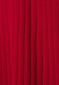 Tissu tricoté rouge présentant une texture côtelée verticale, avec des rainures régulièrement espacées et une apparence douce. Aucune ornementation ou motif notable.