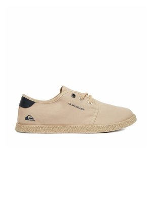 Beige lærred fritidssko med snørebånd, vævet tekstureret sål, sort hælpatch og Quiksilver-logoer på siden og hælen.