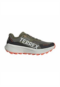 Zapatilla deportiva verde oscura con una parte superior de malla texturizada, puntera reforzada, un destacado logotipo de 'TERREX' y suela de color naranja brillante.