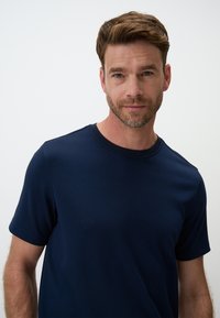 Granatowa, bawełniana koszulka z krótkim rękawem, okrągłym dekoltem i gładką teksturą. Dobrze dopasowany, casualowy styl, z minimalnymi detalami przeszyć.