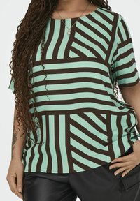 Brown striped pattern t-shirt on a light blue background; short sleeves, round neck, soft fabric, and loose fit design.