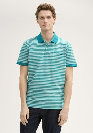 Turquoise en witte gestreepte polo met een effen teal kraag en korte mouwen. Klein borstzakje met logodetail. Gedirigeerd met donkere jeans.