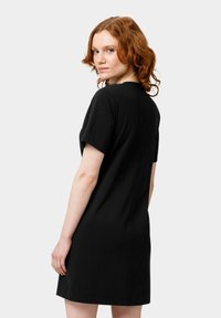 Černé šaty s krátkým rukávem, rovného střihu a minimalistickým designem. Materiál vypadá hladce, s jemnou texturou a bez viditelných vzorů nebo ozdob.