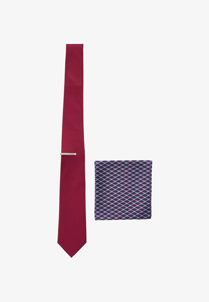 Red textured tie with a silver tie bar beside a navy pocket square featuring a red and white diamond pattern.