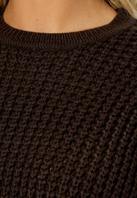 Dunkelbrauner Strickpullover mit strukturiertem Muster, breitem Rippenkragen und einer weichen, warmen Optik.