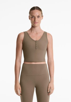 Brown ribbed crop top with a V-neckline and five-button placket. Features wide straps and a fitted design, paired with high-waisted leggings.