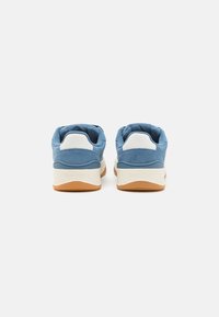 Blå semskede sneakers med hvite detaljer og brune gummisåler. Har en polstret krage og en logo på hælen.