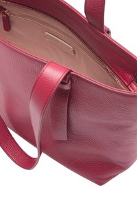 Sac fourre-tout en cuir rouge avec une surface texturée, doté de deux poignées robustes et d'un intérieur lisse avec une poche zippée. Accent de fermeture éclair dorée.