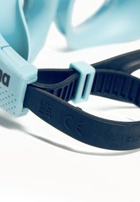 Occhiali da nuoto blu chiaro con cinturino nero regolabile. Realizzati in silicone, includono etichette per la sicurezza, come il marchio CE e la certificazione.