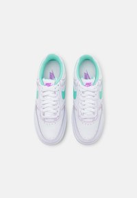 White sneakers with light teal accents, purple logo, and cushioned collar. Features traditional lacing and perforated toe area for ventilation.