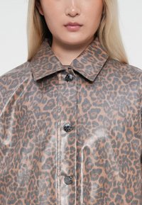 Leopard print coat featuring a glossy finish, large collar, and silver-tone buttons down the front, in shades of brown and gray.