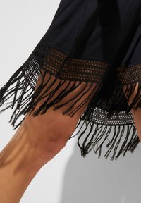 Gonna nera con dettagli di frange intricati all'orlo, caratterizzata da una trama intessuta e un tessuto liscio, che mette in mostra un design a strati.