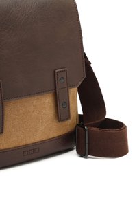 Bolso de hombro de cuero marrón y lona beige con solapa, que presenta herrajes negros, costuras en contraste y una correa de tela.