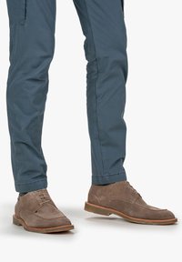 Chaussures en daim marron avec une texture lisse, bout rond et design à lacets. Accents cousus notables et semelle en caoutchouc marron clair.