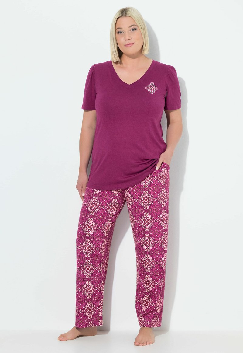 Top morado de cuello en V con mangas cortas abullonadas, combinado con pantalones de lounge sueltos y estampados en rosa que presentan diseños florales blancos.