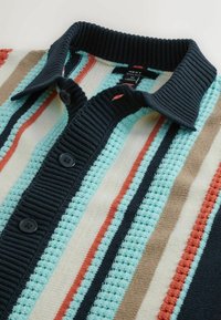 Gestricktes Hemd mit marineblauem Kragen und Knopfleiste, mit vertikalen Streifen in Hellblau, Marine, Weiß, Beige und Rostrot.