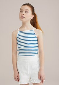 Prugasta majica bez rukava z modro-belimi horizontalnimi črtami, s tankimi naramnicami in oprijetim dizajnom. Na voljo s kratkimi hlačami z belim volančkom.