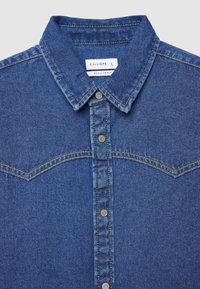 Denimhemd in Dunkelblau mit spitzem Kragen, Knopfleiste und Western-Stil Passe. Mit kontrastierenden Nähten und Metallknöpfen.