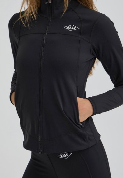 Juodas zip-up džemperis, pagamintas iš lygaus, elastingo medžiagos. Įrengtas šoninėmis kišenėmis, siūlėmis ir mažuoju logotipu ant krūtinės.