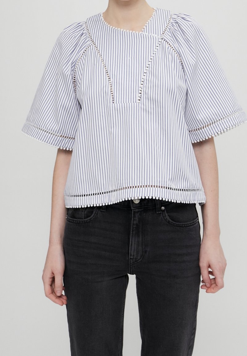 Blouse à manches courtes rayée blanche et bleu marine, avec un décolleté carré, une bordure en dentelle à l'ourlet, et des manches bouffantes à coupe décontractée.