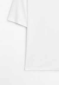 Krátký rukáv, bílý tričko vyrobené z měkké bavlny. Kulatý výstřih, jednoduchý design, hladká textura a rovný lem bez vzorů nebo akcentů.