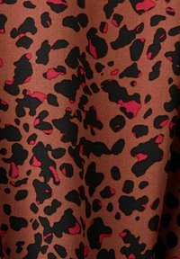 Tissu léopard dans des nuances de marron, noir et rouge. Présente des formes irrégulières et audacieuses avec une texture lisse.