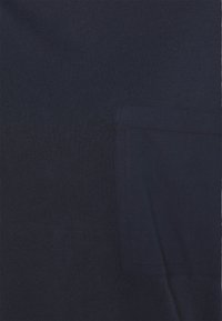 Granatowa bawełniana koszulka z teksturowanej tkaniny, z prostokątną kieszonką i prostymi szwami wzdłuż krawędzi.