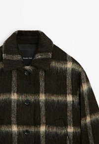 Manteau à carreaux duveteux marron foncé avec boutons noirs et large col, présentant des carreaux beige clair et gris, de la marque Massimo Dutti.